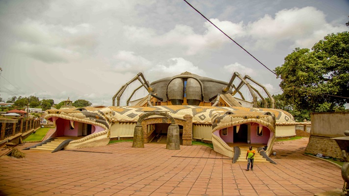 a man standing in front of a building with large spiders